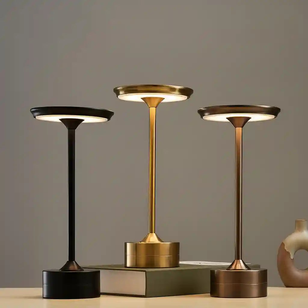 Three modern table lamps in black, gold, and bronze on a neutral background